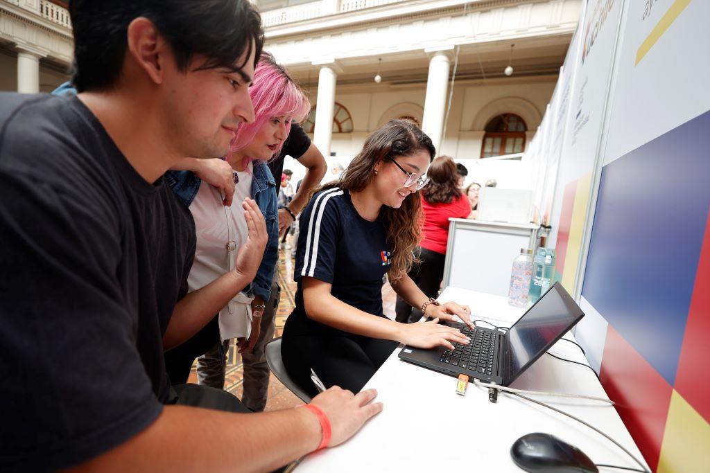 Monitora en computador y familia mirando, todos sonriendo, en el contexto de matrícula 2024