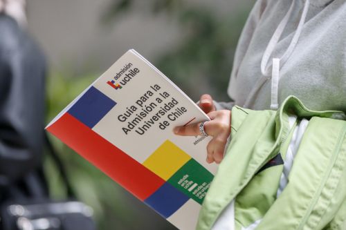 Se ven las manos y parte del torso de una postulante sosteniendo la publicación: Guía para la admisión a la Universidad de Chile