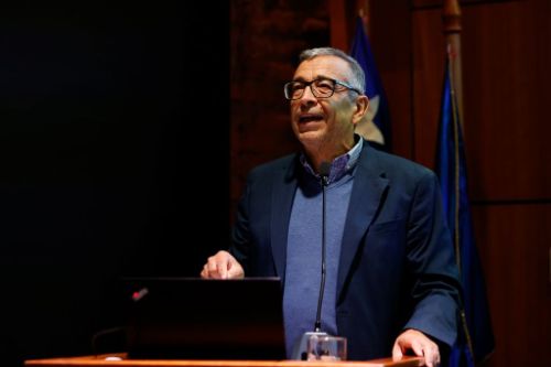 Plano medio de Andeljalil Akkari, hablando en la testera del auditorio de la Facultad de Arquitectura y Urbanismo de la Universidad de Chile