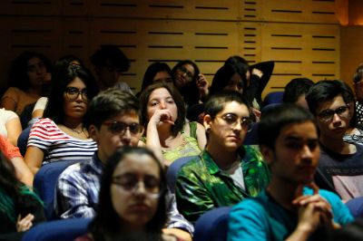 Estudiantes sentados en un auditorio, mirando con atención, en el contexto de una ceremonia de Inducción a la U. de Chile