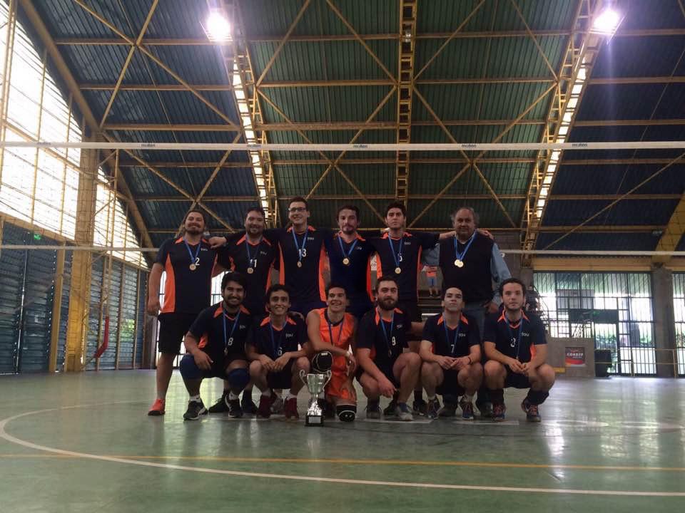 Equipo de voleibol posando junto a la copa y las medallas.