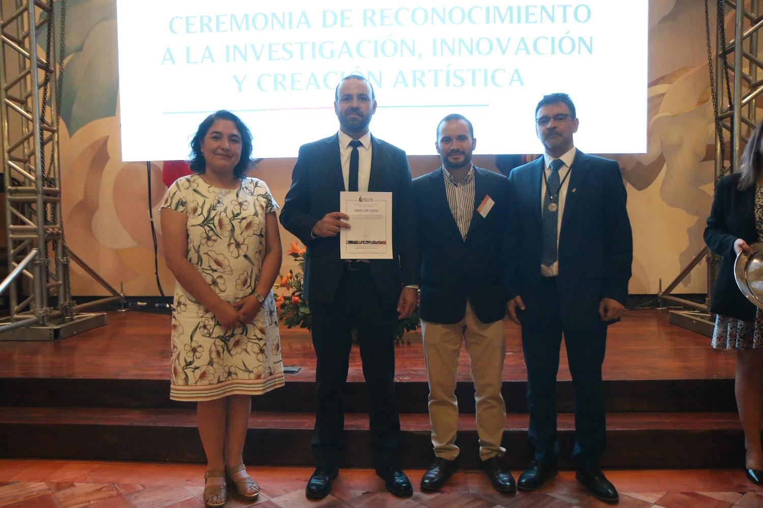 Dra. Alicia Valdés -en representación del Decano Mario Maino- junto al Vicerrector Flavio Salazar y el Jefe de Transferencia Teconológica de la VID, Gaspar Morgado, galardonan Dr. Leonardo Saénz.