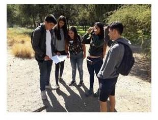 Grupo de estudiantes haciendo ejercicio de orientación en campo abierto.