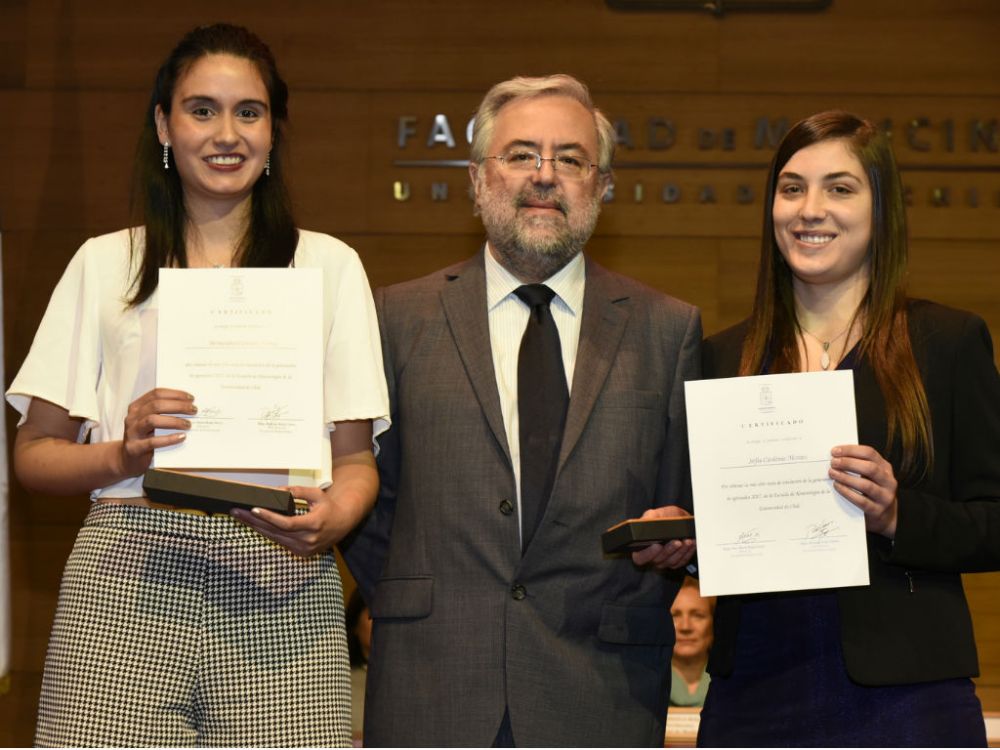 Bernardita Carrasco y Valentina Miranda recibieron su premio como mejores egresadas de manos del decano de la Facultad de Medicina, doctor Manuel Kukuljan.