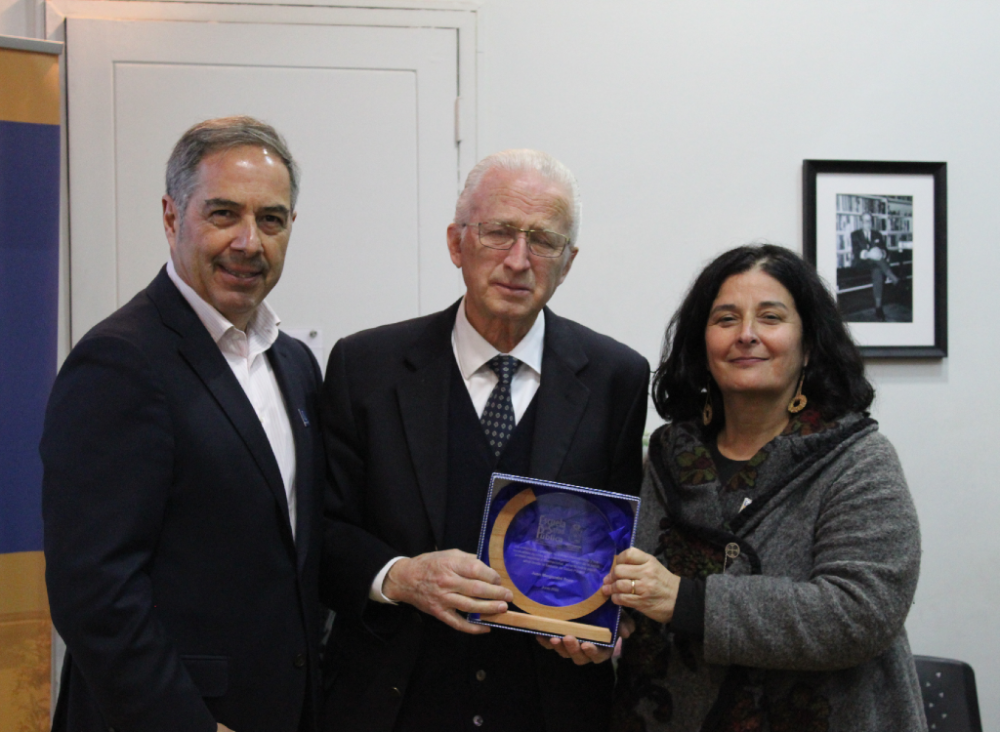 Doctores Miguel O'Ryan, decano de la Facultad de Medicina, y Lorena Rodríguez, directora de la ESP, premian la trayectoria del doctor Juan Margozzini. 
