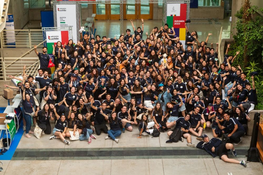 Grupo de alrededor de cien monitoras y monitores Uchile, posando desordenados a la cámara en una Semana de las y los postulantes Uchile