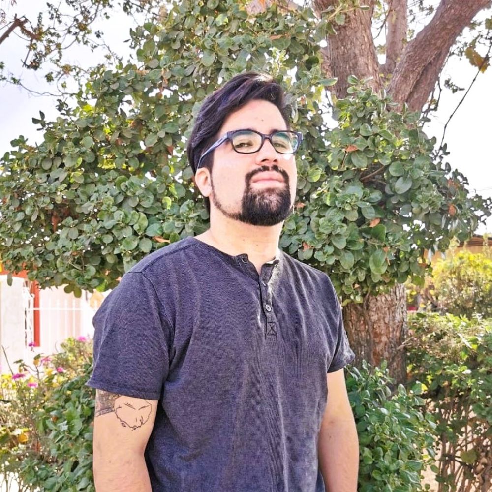 Foto de medio plano de Hans Klener mirando a la cámara. Al fondo se ven árboles