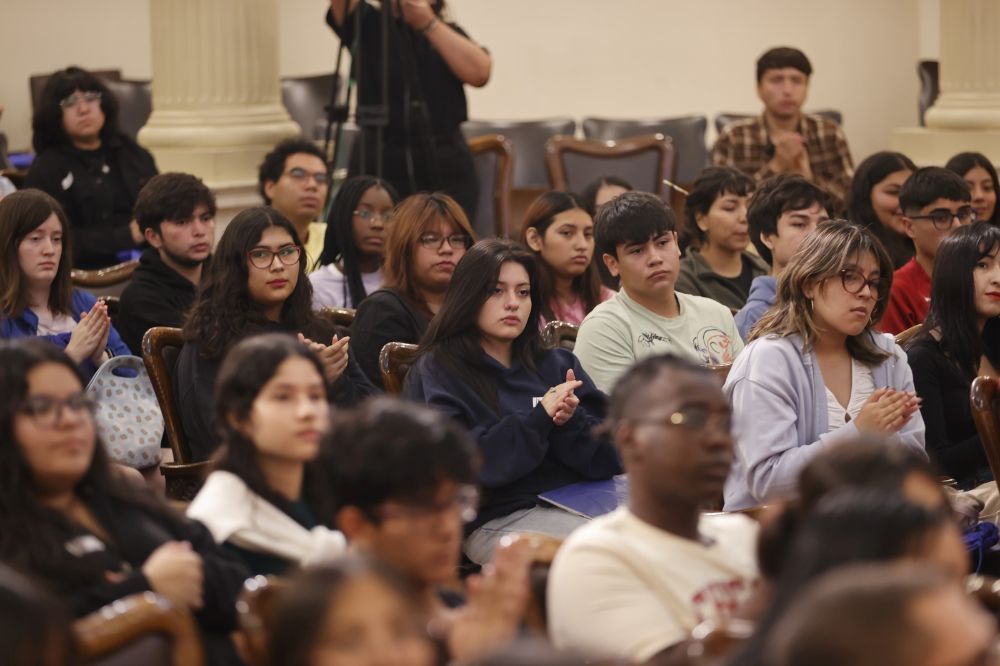 Estudiantes sentados, mirando hacia el frente en el Salón de Honor de la U. de Chile