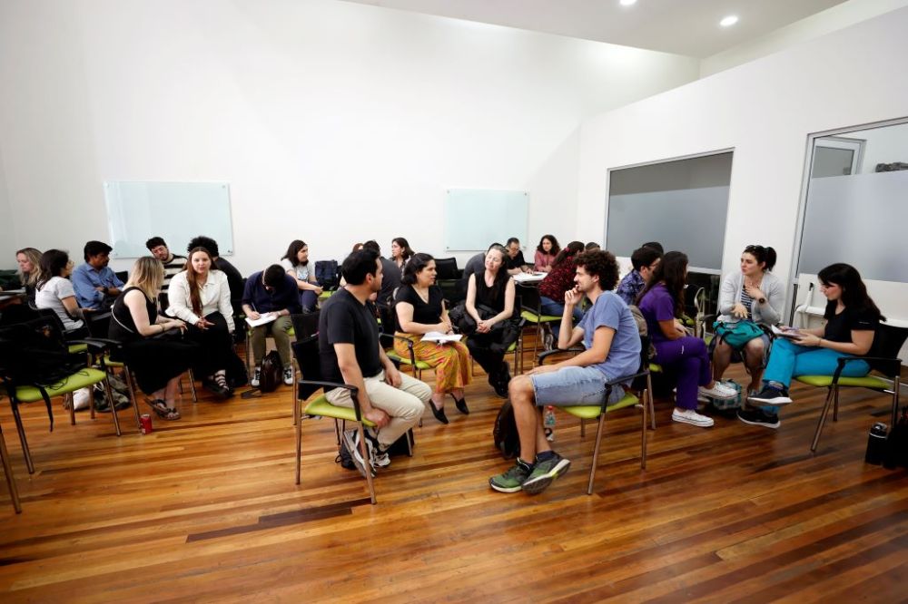 Sala con diferentes grupos de profesoras y profesores conversando en círculo.