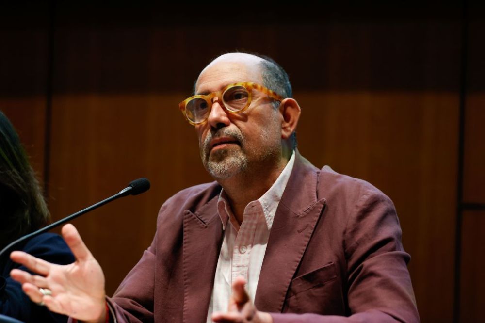 Medio plano corto del profesor Olea, hablando al micrófono