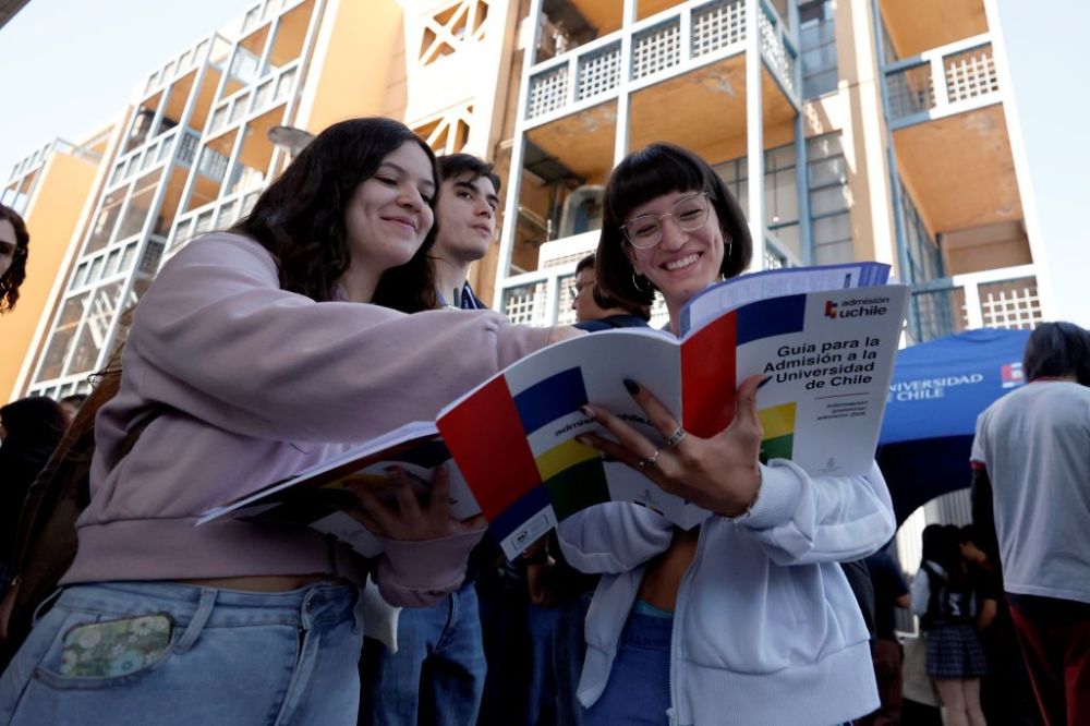 Estudiantes observan sonrientes la guía de admisión a la U. de Chile