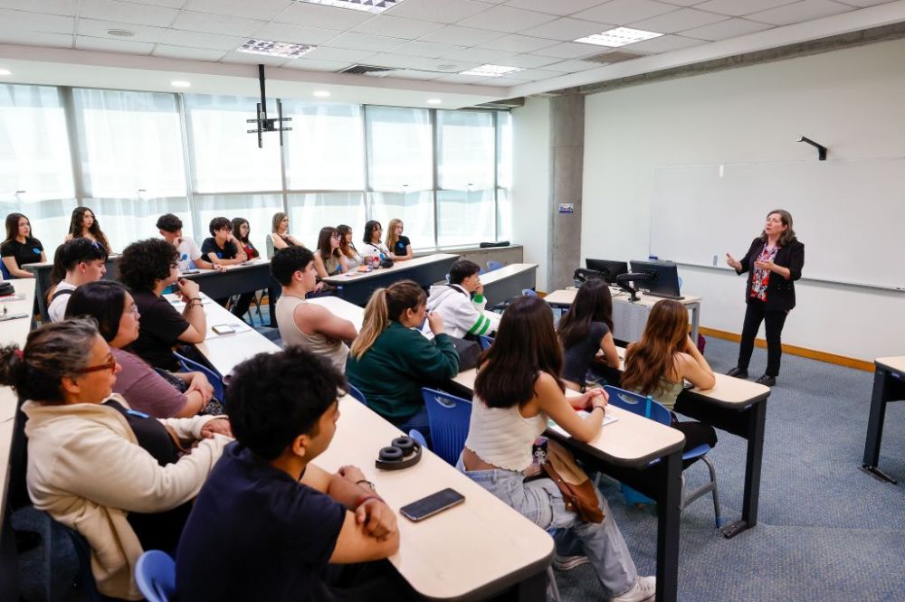 Charla en sala de FEN, se ve a la relatora hablando y a las y los escolares tomando atención desde sus asientos
