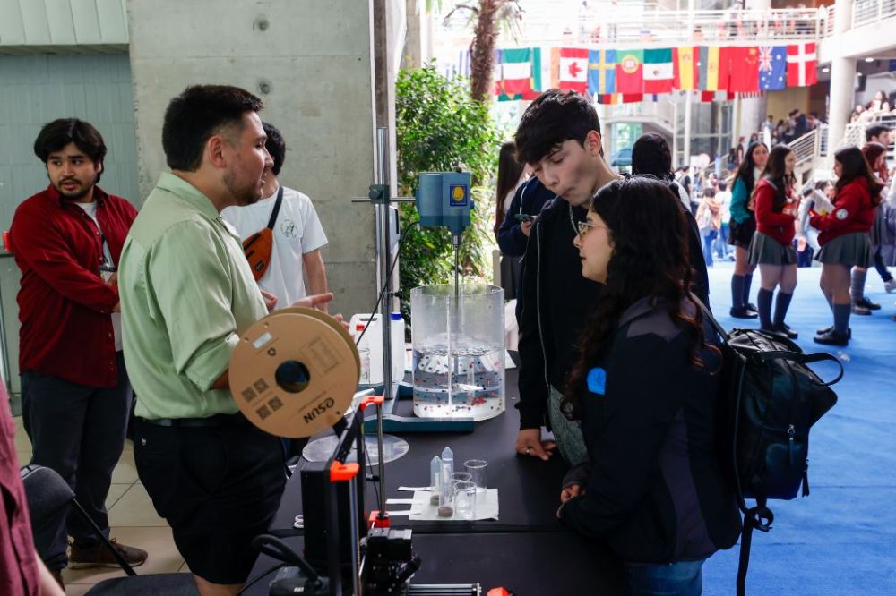 Stand de actividades interactivas, donde miembros de la FCFM explican experimentos a escolares asistentes