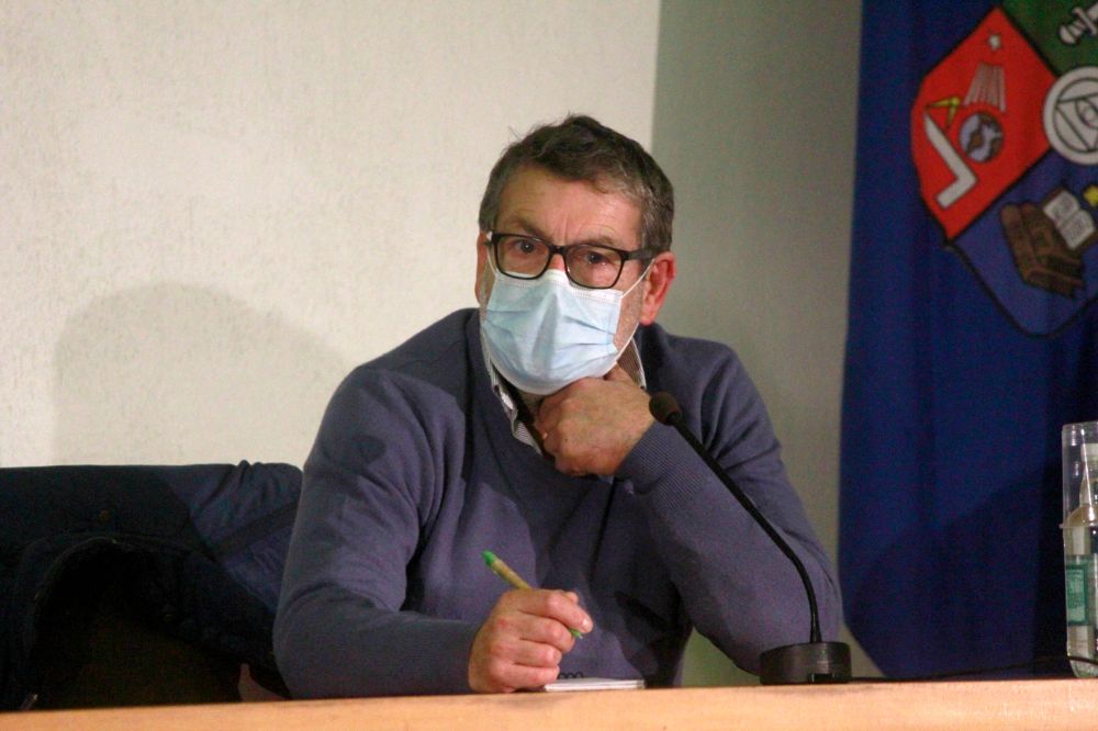 Académico Óscar Mercado, sentado en la testera, con mascarilla, escuchando una pregunta