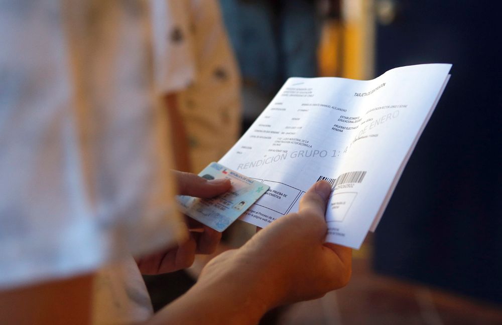 Primer plano de la mano de un estudiante sosteniendo su tarjeta de identificación y carnet para rendir la PDT