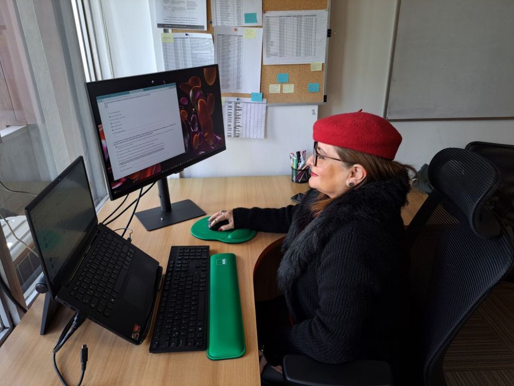 Profesora sentada frente a un computador, respondiendo la autoevaluación docente