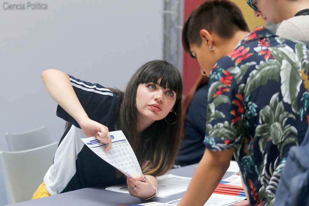 Monitora de la Facultad de Gobierno de la U. de Chile le explica malla a postulante que la mira con atención.