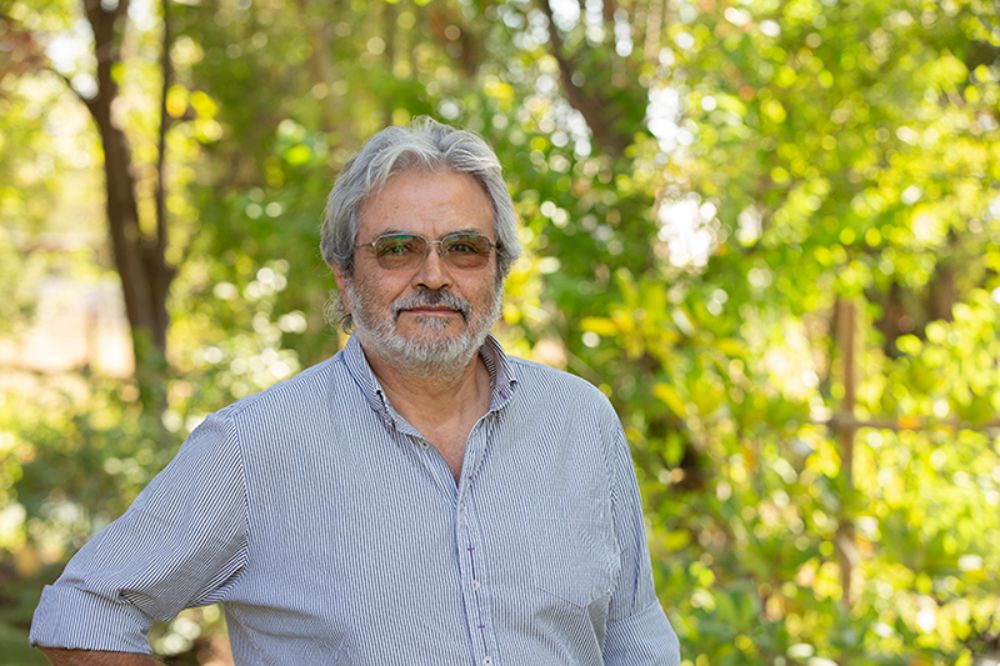 Ramiro Bustamante posando detrás de un fondo de arboles 