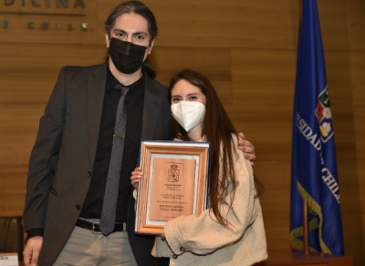 La tecnóloga Médica Katerina Lizama recibe su distinción como Mejor Rendimiento Académico 2020 de manos del director de Investigación, doctor Leandro Carreño. 