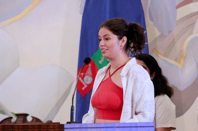 Plano medio de Josefa Fernández, presidenta del Centro de Estudiantes de Derecho y miembro de la Coordinación del Consejo de Presidencias de la FECH, hablando en la testera del Salón de Honor de Casa Central de la U. de Chile