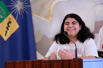 Plano medio de Amaranta Godoy, presidenta del Congreso Fech, hablando en la testera del Salón de Honor de Casa Central de la U. de Chile.