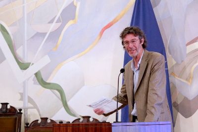 Plano medio del vicerrector Claudio Pastenes, hablando en la testera del Salón de Honor de Casa Central de la U. de Chile.