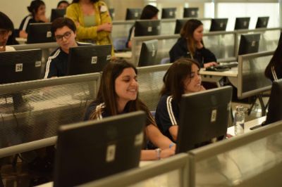 Monitoras y monitores, de admisión Uchile, en sala de computación, respondiendo chats