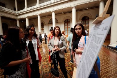 Expositoras de póster, explicando a asistentes en el patio Bello