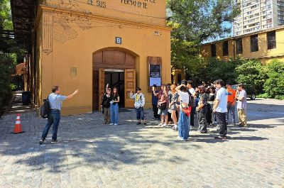 Grupo de estudiantes en frente al auditorio de la Facultad de Arquitectura y Urbanismo, haciendo un tour por la Semana de las y los Postulantes de la U. de Chile 2025