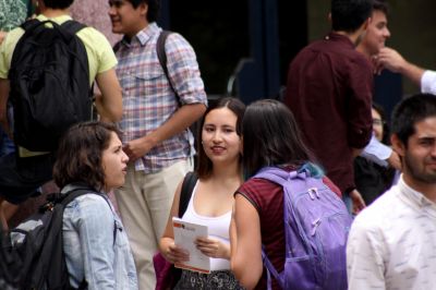 Estudiantes conversando en un patio. La atención se centra en tres estudiantes mujeres conversando.