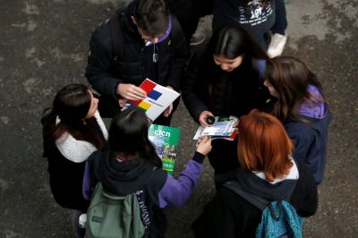 Desde arriba se ve a un grupo de estudiantes en cículo, con guías en admisión en sus manos, conversando