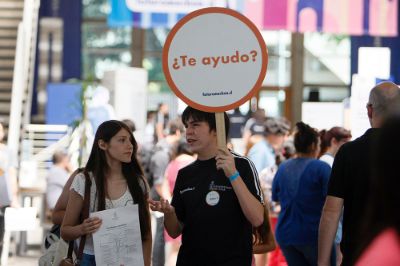 Un monitor, con una paleta que dice ¿Te ayudo?, conversa con una postulante