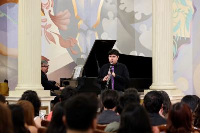 El clarinetista con discapacidad visual, Bernabé Catalán y el pianista, Rodrigo Palacios, estudiantes de la carrera de Interpretación Musical de la Facultad de Artes, frente a la audiencia del Salón de Honor.