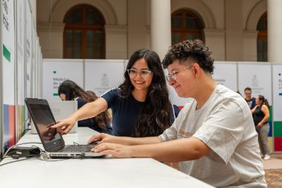 Monitora orientando a mechón para matricularse en la U. de Chile, frente a un notebook