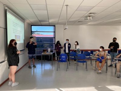 Estudiantes exponiendo y otros escuchando, al interior de una sala de la Universidad del Bío-Bío, donde también se ve a Joaquín Díaz.