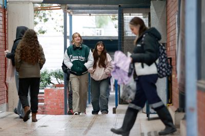 Grupo de siete estudiantes, posando con una sonrisa, con dos computadores al frente y las banderas de Chile y la Universidad de Chile, detrás