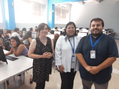 Parte del equipo de trabajo que trabajó en el desarrollo de los cursos: Catalina Marilao (VTI), Inés Zulantay (IR Proyecto FIDOP), Braulio Ibarra (VTI). Atrás las y los alumnos trabajan en una de las salas de computación de la Facultad de Medicina