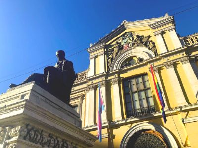 Frontis de la Casa Central de la U. de Chile con las banderas LGBT y trans